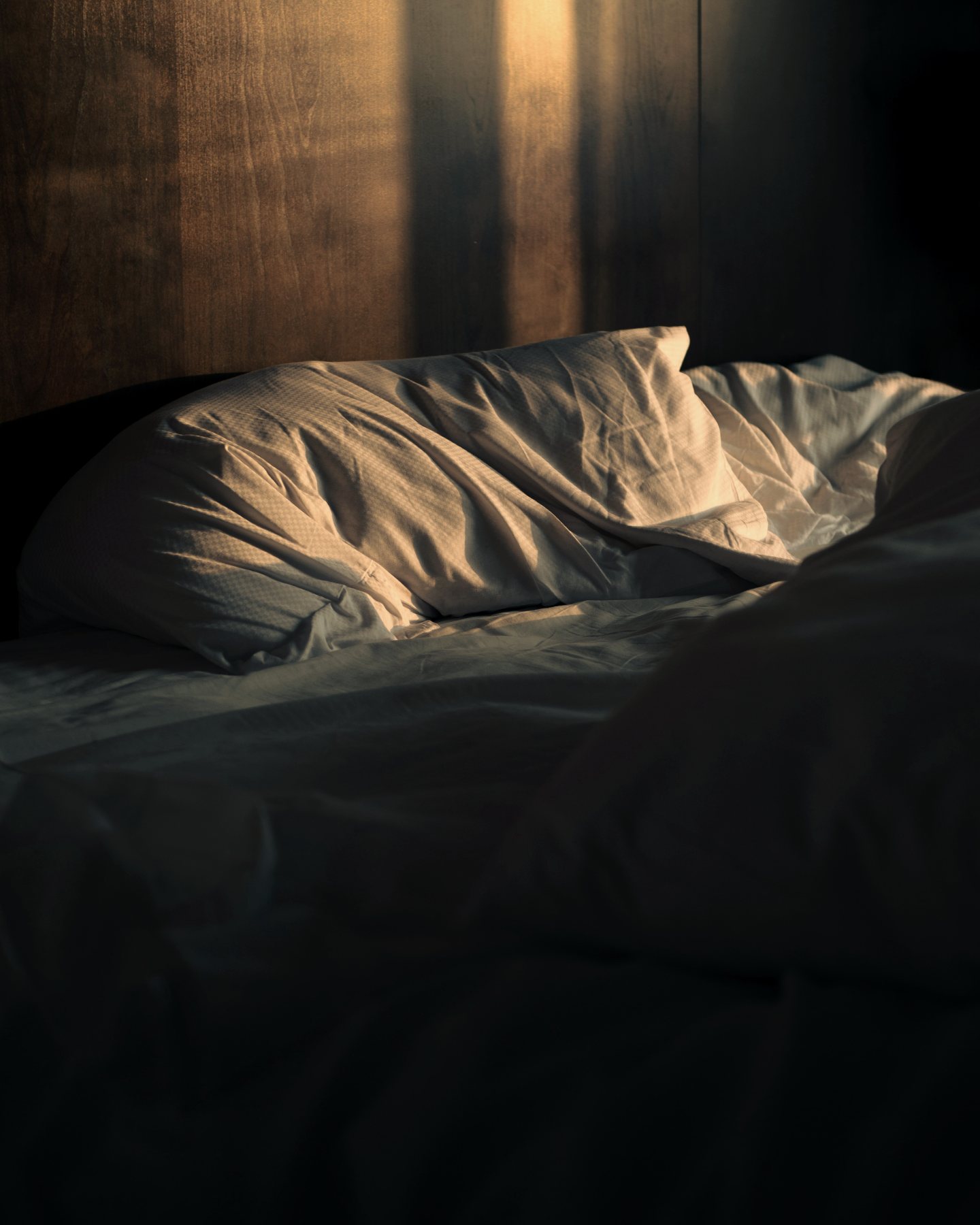 Morning light across an unmade bed